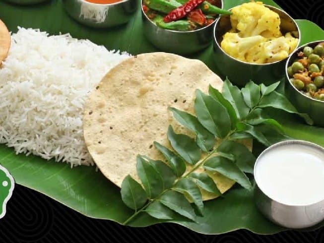 Thanjai's medley platter: rice, poori, pappadam and small bowls of curries on a banana leaf